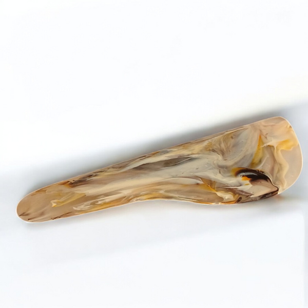A marbled beige and light brown rectangular hair clip with rounded edges, echoing the elegant style of the Nashi Home Arila Cheese Knife - Mocha, rests gracefully on a white surface.