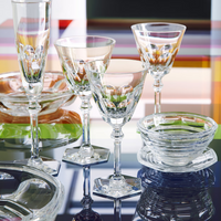 The Baccarat Harcourt Eve Flutes Set of 2, along with other crystal glassware, is elegantly arranged on a reflective surface.
