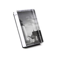 The Simon Pearce Woodbury Photo Block Vertical is a rectangular, handcrafted, lead-free glass plaque featuring a black-and-white lighthouse image under clouds. The angled design displays "ON PEACE" and other small text at the bottom.