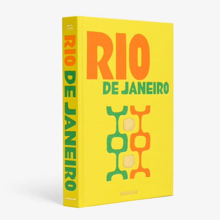 A bright yellow hardcover book, "Travel Series - Rio de Janeiro Viva" by Assouline, features bold orange and green text with abstract geometric designs on the front cover and stands upright with its spine visible.
