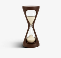 The Assouline Mirage Luxury Leather Hourglass features light sand and a sleek dark brown leather exterior, elegantly displayed on a white background—an ideal decorative timer for any space.