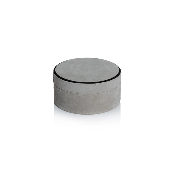 The Aldo Suede Box Grey by Zodax is a round, light gray suede leather storage box with a matching lid and subtle black trim, offering minimalist elegance.