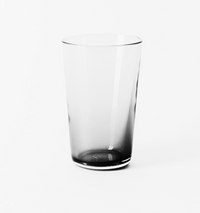 The Gary Bodker Everyday Glass Clear is an elegant, transparent drinking glass with a subtly darkened base, standing upright on a white surface—an ideal addition to your stylish everyday glassware collection.