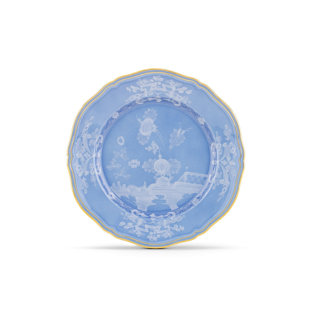 The Ginori 1735 Oriente Italiano Pervinca Dinner Plate features a round blue design with white floral and landscape patterns, a yellow-rimmed edge, and elegant 24-karat gold trim, displayed on a plain white background.