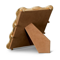 The L'Objet Ripple Frame Gold features a modern wavy-edge design. Its back and stand are covered in brown suede-like material, letting the frame stand upright on flat surfaces.