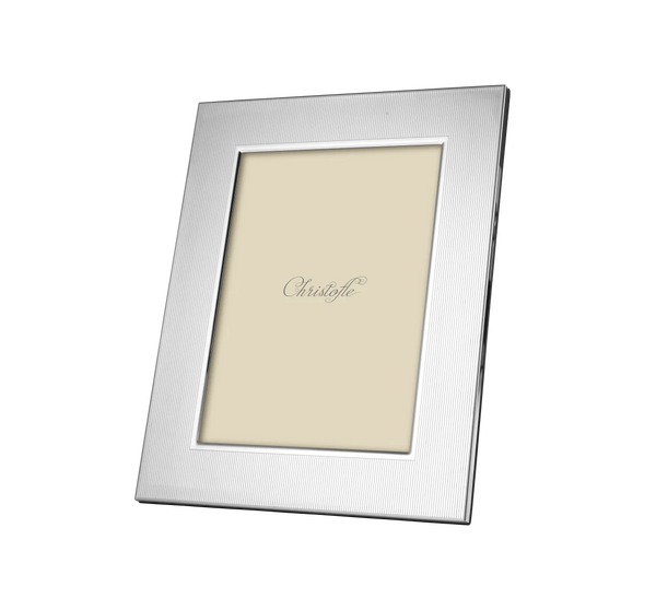 The Christofle America Stainless Steel Frame features a silver rectangular design with a simple, textured border, displayed at an angle on a white background. Inside is a beige placeholder with “Christofle” in elegant script.