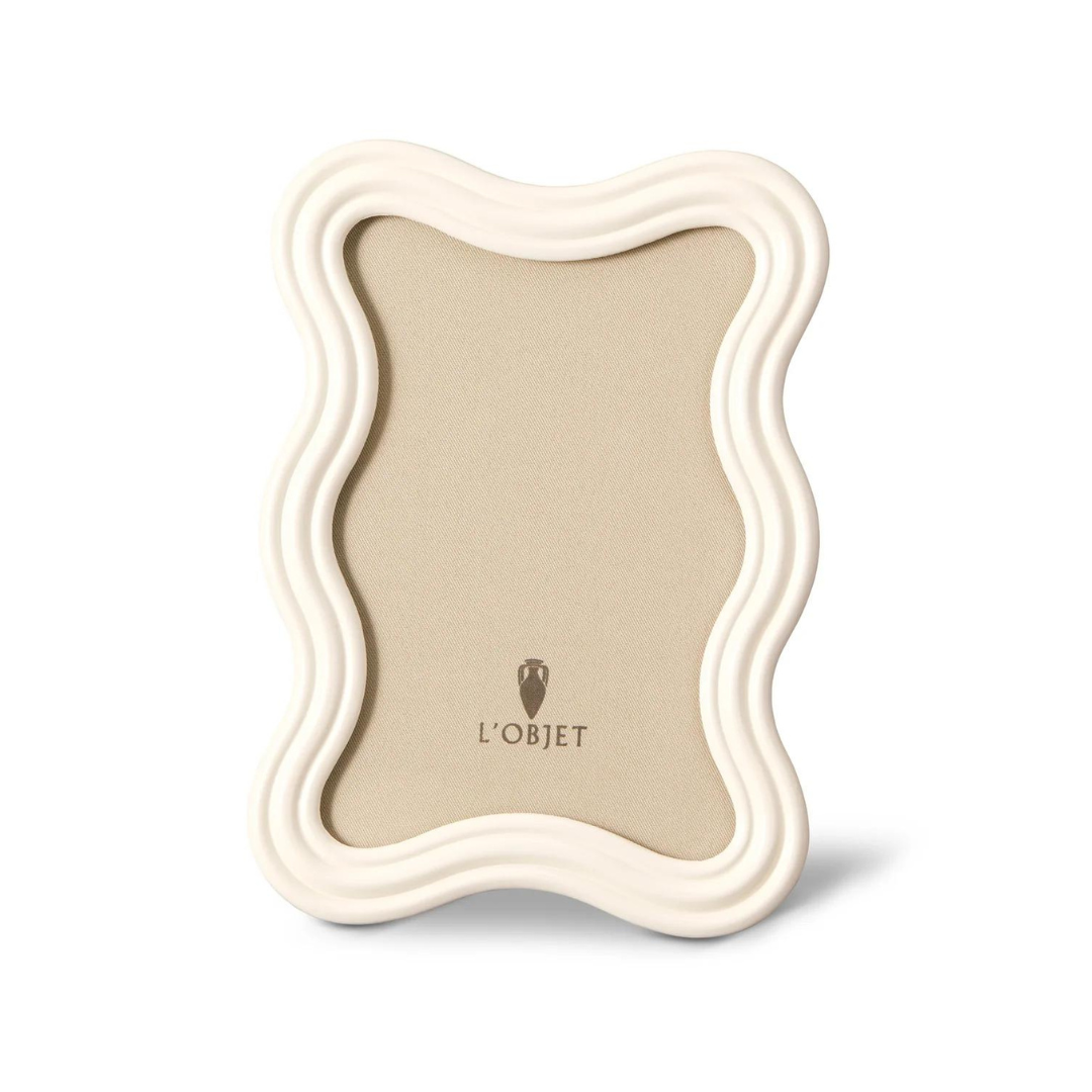 The Ripple Enamel Frame White by L'Objet features a wavy white enamel design, handcrafted in Portugal, with a tan backing and the L'Objet logo at the bottom.