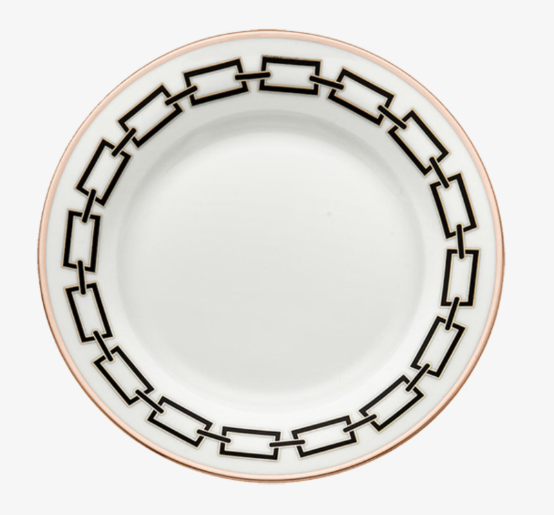 The Catene Nero Dinnerware by Ginori 1735 features a white ceramic plate adorned with a geometric black border pattern around the rim and finished with a thin gold edge.