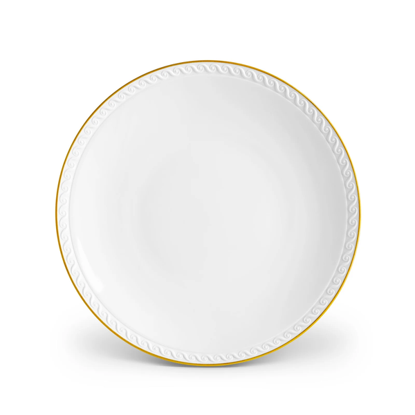 The L’Objet Neptune Gold dinnerware plate is crafted from fine white porcelain with a 24k gold rim and a textured wave pattern along the edge, displayed against a white background.
