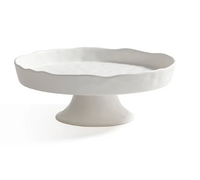 The Zodax Alto Ceramic Pedestal Bowl features a white ceramic finish with a wavy edge and wide base, serving as an elegant centerpiece or serving dish, perfect for displaying treats on any table.