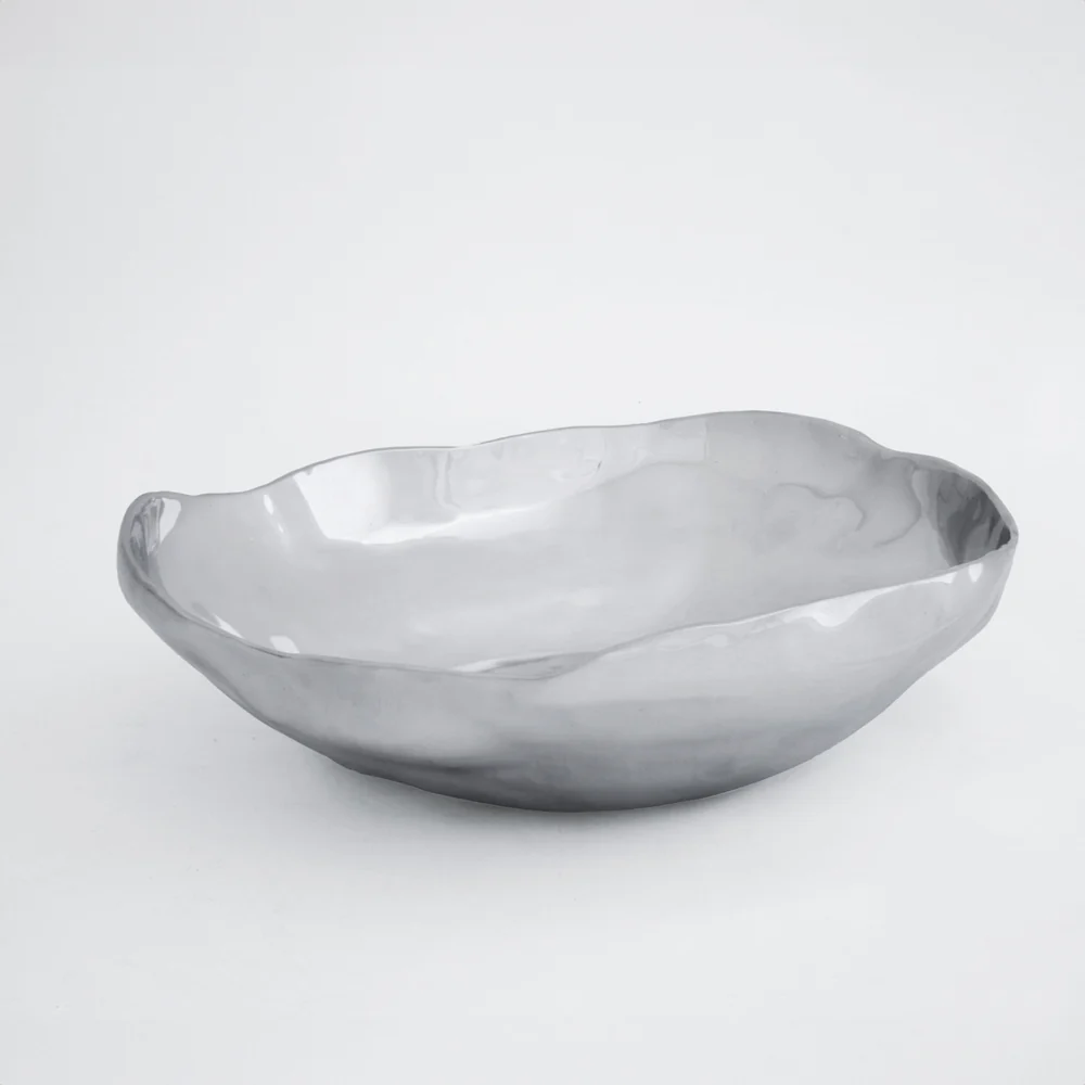 The Beatriz Ball Soho Nueve Organic Bowl 12.5" is a shiny, handcrafted metal bowl with smooth, curved edges and an irregular shape, shown on a plain white background.
