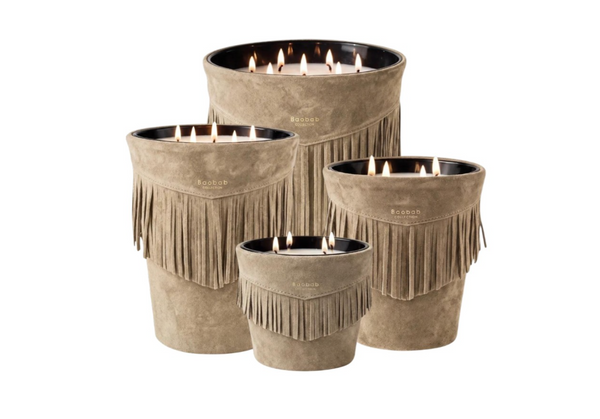 Four lit Baobab Calamity Jane Candle - The Plains in mineral taupe suede containers decorated with fringe.