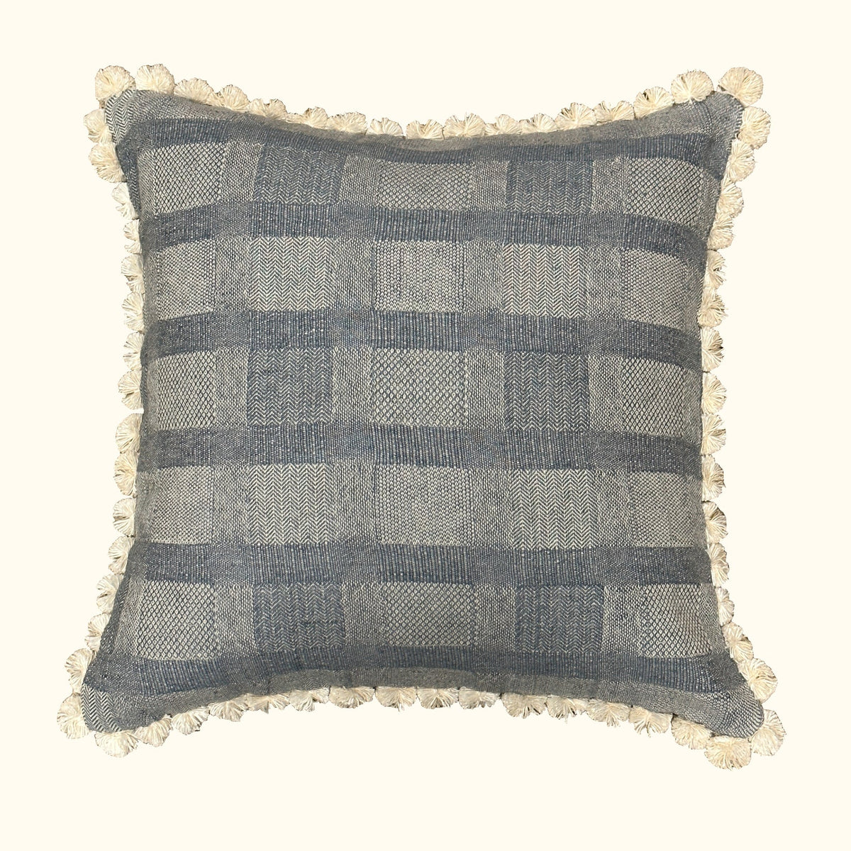 The Drift Azure Pillow by Threads Soft Goods features a blue and beige plaid pattern with a woven texture, playful ivory fabric loops along the edges, an off-white background, and measures 22 x 22 inches.