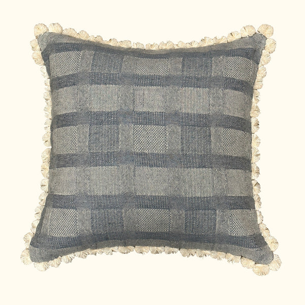 The Drift Azure Pillow by Threads Soft Goods features a blue and beige plaid pattern with a woven texture, playful ivory fabric loops along the edges, an off-white background, and measures 22 x 22 inches.