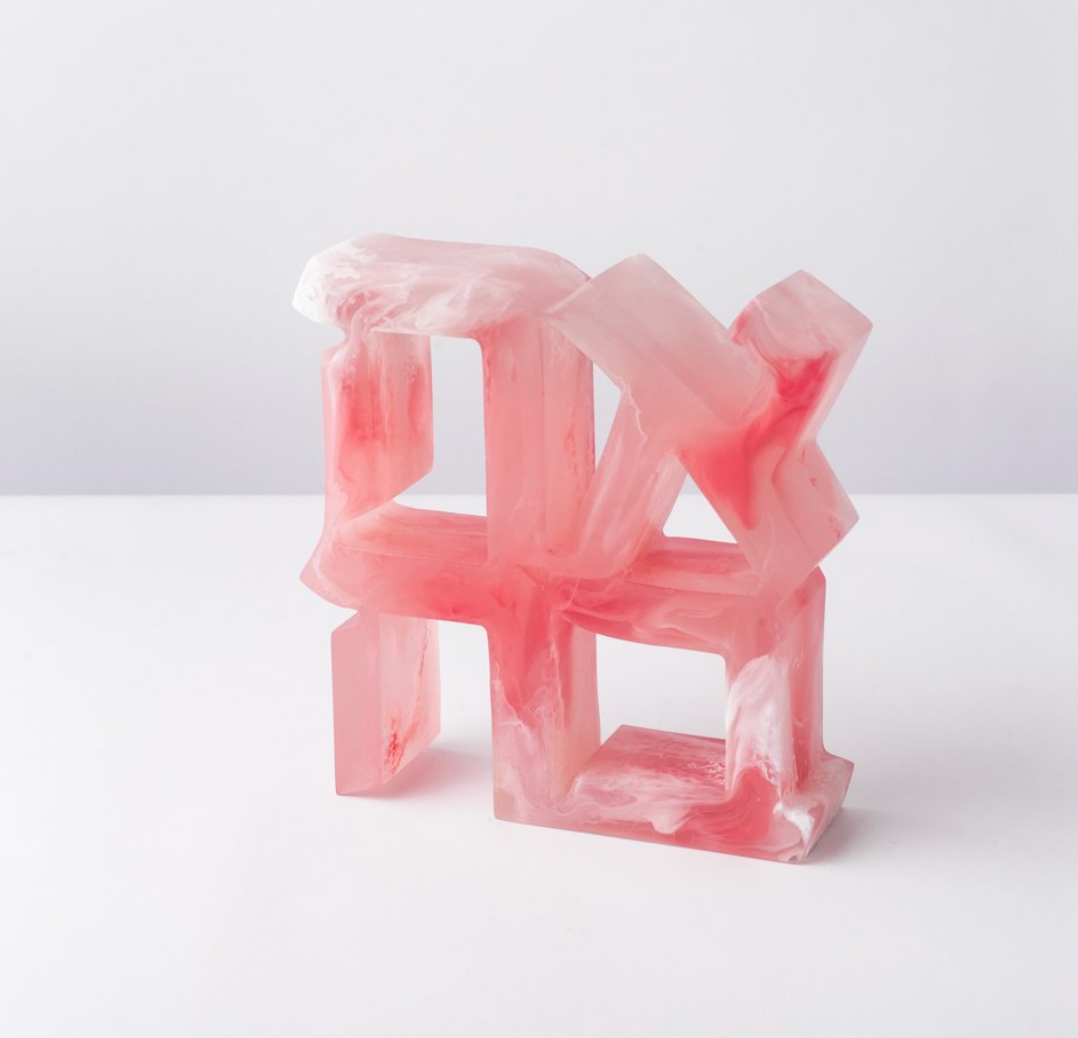 The Ahava Sculpture by CDMX / BRUCI, now back in stock, features a geometric interlocking design in translucent resin with pink and white swirls, shown against a plain white background.