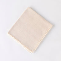 The Dove & Donkey Hemstitch Classic Napkin Cloud Set of 4 features hand-finished, neatly folded off-white napkins with frayed edges, styled on a plain white background.