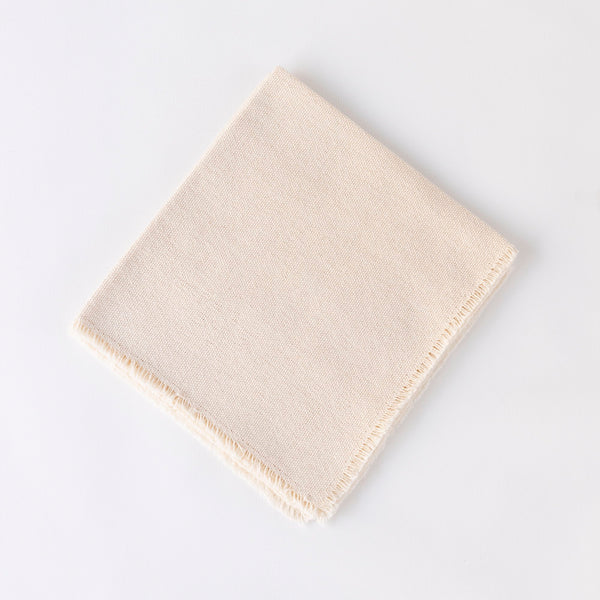 The Dove & Donkey Hemstitch Classic Napkin Cloud Set of 4 features hand-finished, neatly folded off-white napkins with frayed edges, styled on a plain white background.