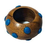 The Candy Dots Napkin Ring Set of 4 by Von Gern Home features round, wooden rings with a smooth finish and raised blue dots evenly spaced around the surface, plus a wide central opening for colorful table decor.