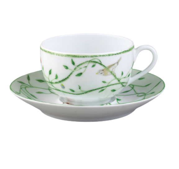 The Histoire Naturelle Dinnerware by Raynaud features a white porcelain teacup and saucer adorned with green vines, leaves, and rare birds—elegantly crafted to add a touch of French excellence to your dining experience.