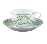 The Histoire Naturelle Dinnerware by Raynaud features a white porcelain teacup and saucer adorned with green vines, leaves, and rare birds—elegantly crafted to add a touch of French excellence to your dining experience.
