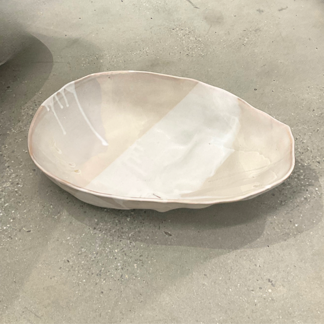 The Ripple Oval Large Bowl by Alex Marshall Studios is a handmade ceramic piece with an irregular shape and glossy off-white finish, ideal as an oversized serving bowl for salads.