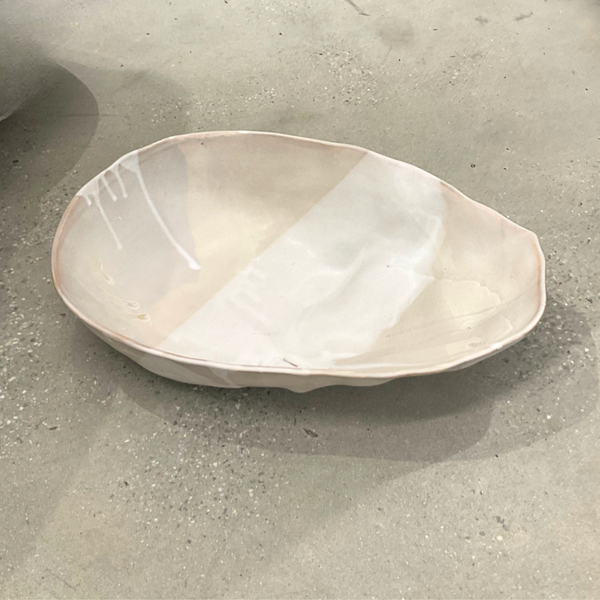 The Ripple Oval Large Bowl by Alex Marshall Studios is a handmade ceramic piece with an irregular shape and glossy off-white finish, ideal as an oversized serving bowl for salads.
