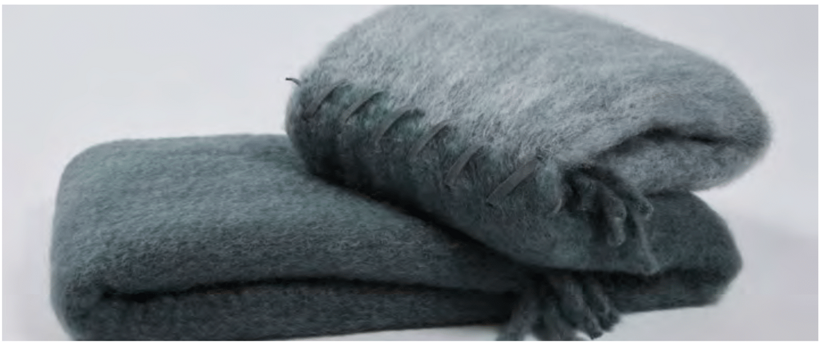 Two grey Stitching Throw blankets by Mantas Ezcaray—one folded and stacked, the other draped with fringe—displayed against a plain white background.