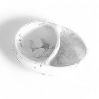 The Nashi Home Arila Split Bowl – White Swirl, shown on a white background, features an oval shape with a marbled design and two compartments—ideal for serving and adding coastal style to your table.