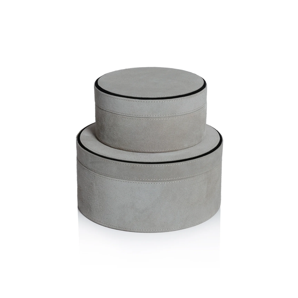 Two round Aldo Suede Box Grey decorative boxes by Zodax are stacked, with the smaller on top. Both feature light gray suede leather and black-trimmed edges, creating a minimalist storage set against a white background.