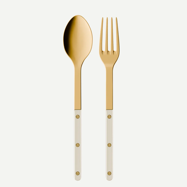The Bistrot Gold Pearly Serving Set - Pearl by Sabre, featuring gold-colored spoon and fork with white handles and gold rivet details, is displayed side by side on a plain white background.