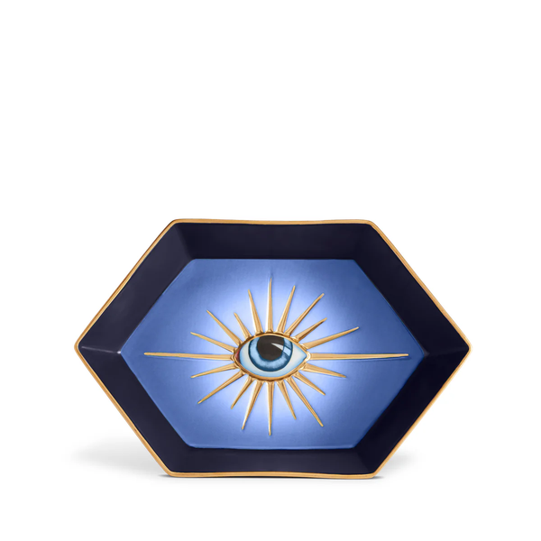 The L’Objet Lito Eye Hexagon Tray is a striking hexagonal porcelain catchall with a gradient blue background, 24-karat gold trim, and a stylized eye surrounded by gold rays.