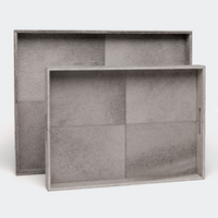 Made Goods Renard Rectangle Hide Grey Trays in silver-gray feature textured leather surfaces, visible panel seams, and convenient side handles—one tray stands upright behind the other, which lays flat and angled forward.