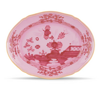 The Ginori 1735 Oriente Italiano Porpora is an ornate oval porcelain plate with a pink background, chinoiserie floral and landscape motifs, detailed border patterns, and a thin yellow rim.