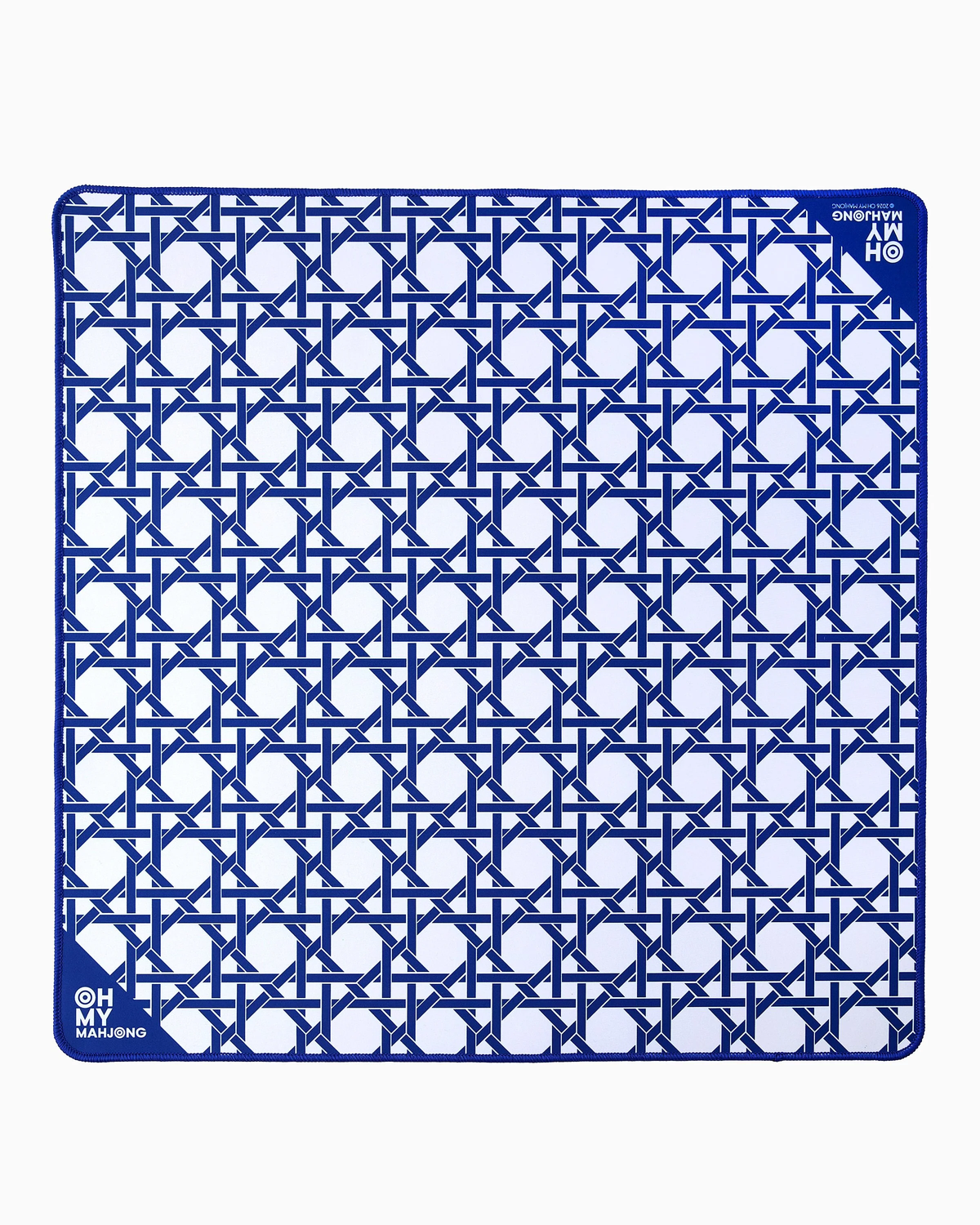 The Oh My Mahjong Travel Mini Mahjong Game Mat is a 22” x 22” square blue and white mat with a geometric pattern of interlocking lines and circles. Its corners feature small circular logos reading “OH! MY MAHJONG” and “MAHJONG.”.