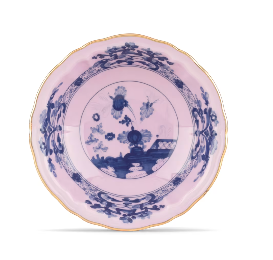 The Oriente Italiano Dinnerware Azalea by Ginori 1735 features a pink porcelain plate adorned with blue floral and butterfly designs, gold-trimmed scalloped edges, and is inspired by the renowned Ginori Oriente collection.