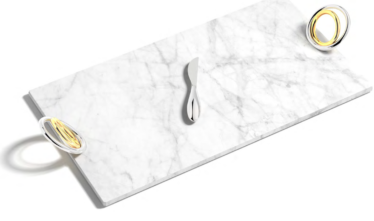The Anna New York Ring Cheeseboard & Knife Set is a rectangular marble board featuring a stainless steel knife at the center and two metallic rings with yellow accents on opposite corners.