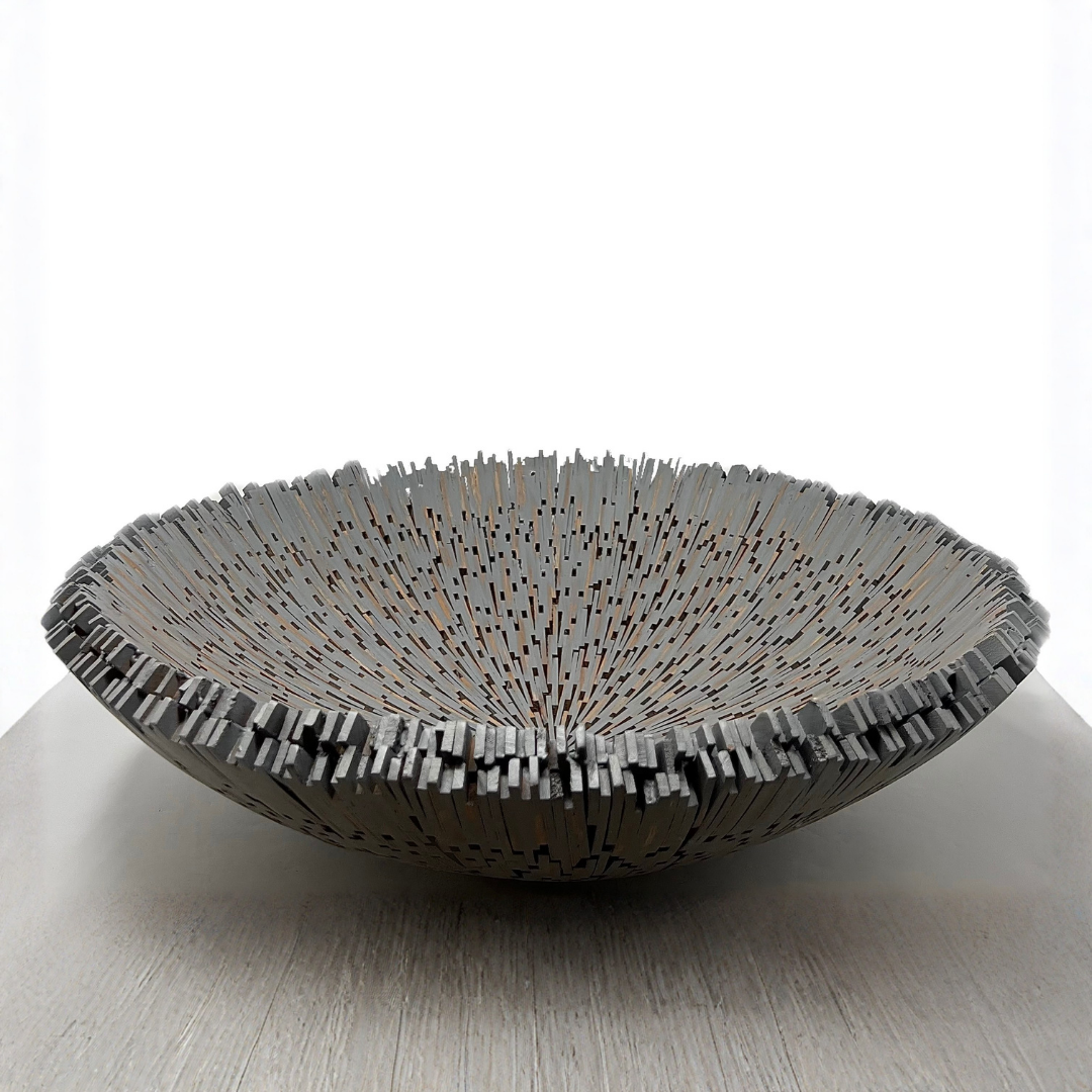 The Boracay Centerpiece Bowl by Lily Juliet is a shallow, round metal bowl with a spiky, irregular rim and thin vertical details, displayed on a light surface against a white background.
