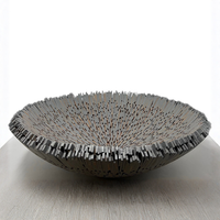 The Boracay Centerpiece Bowl by Lily Juliet is a shallow, round metal bowl with a spiky, irregular rim and thin vertical details, displayed on a light surface against a white background.