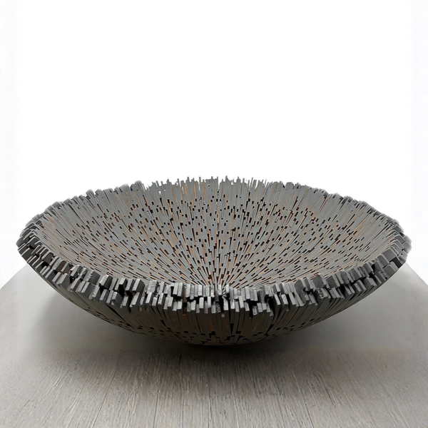 The Boracay Centerpiece Bowl by Lily Juliet is a shallow, round metal bowl with a spiky, irregular rim and thin vertical details, displayed on a light surface against a white background.