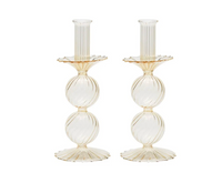 The Bella Candlestick Holder Set of 2 by Kim Seybert showcases two elegant candlestick holders crafted from hand-blown glass, featuring ribbed, spherical shapes stacked vertically and a fluted base, displayed against a plain white background.