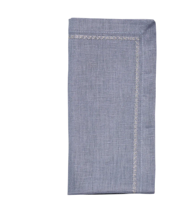 The Kim Seybert Classic Napkin - Dusty Blues (Set of 4) features a folded light blue cloth with a decorative stitched border, shown against a white background.