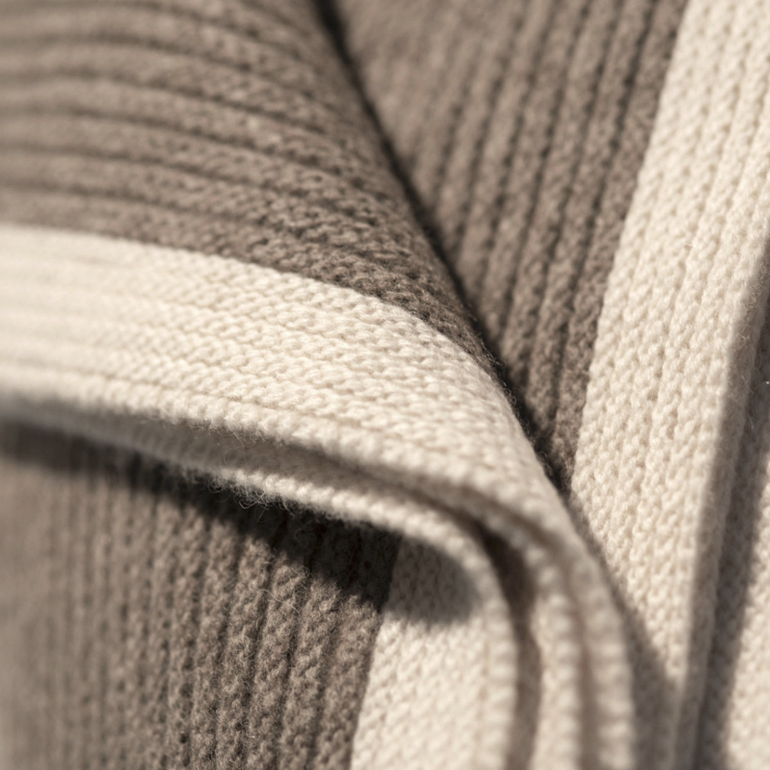 Close-up of a Yak Ribbed Platinum & White Throw, shown folded to display the ribbed, taupe fabric and thick, cream-colored border.