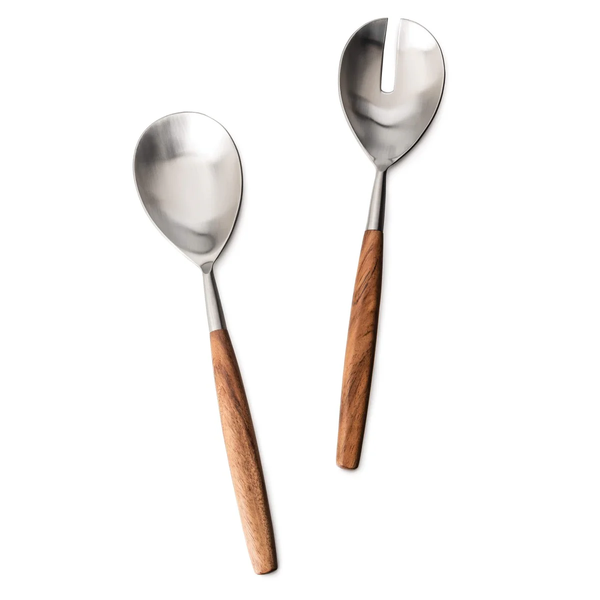 The Simon Pearce Barre 2pc Serving Set features two serving utensils with stainless steel heads and wooden handles; one is a solid spoon, and the other has a single slot, making it perfect for serving salads. Both pieces are displayed on a white background.