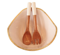 The Montauk Serving Bowl With Servers by Indy Home features a white bowl with a gold rim, holding a handmade wooden salad spoon and fork with white handles, placed side by side inside the bowl.