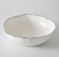 The PAMPA BAY Portofino Plata Bowl, a white porcelain medium serveware piece with a wavy silver trim, rests elegantly on a white surface.