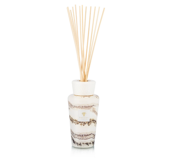 The Baobab Sand Siloli Diffuser features wooden sticks in a white, marbled glass bottle, elegantly displayed on a white background and filling the room with a luxurious fragrance of cedarwood and tonka bean.