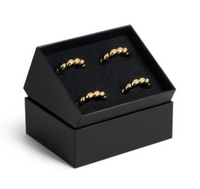 Four gold-toned, shell-shaped L’Objet Jessica McCormack Shell Napkin Ring s/4 - Gold arranged inside a black presentation box.