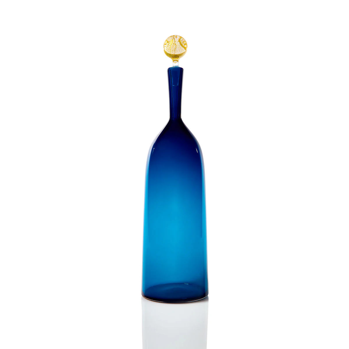 A tall steel blue glass bottle from Cariati’s Carmella Decanters collection, featuring a long neck and round textured gold stopper, stands upright against a white background.