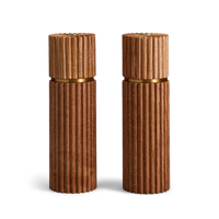 The Ionic Salt & Pepper Mill Set by L'Objet features two matching cylindrical mills in natural European oak with vertical grooves and gold accents, displayed side by side against a white background.