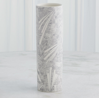 The Global Views/Surya Searchlight Vase, a tall cylindrical white piece with abstract black geometric and leaf-like designs, stands on a light surface against a softly striped background.